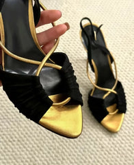 Close-up on the front of black and gold stiletto heeled sandals