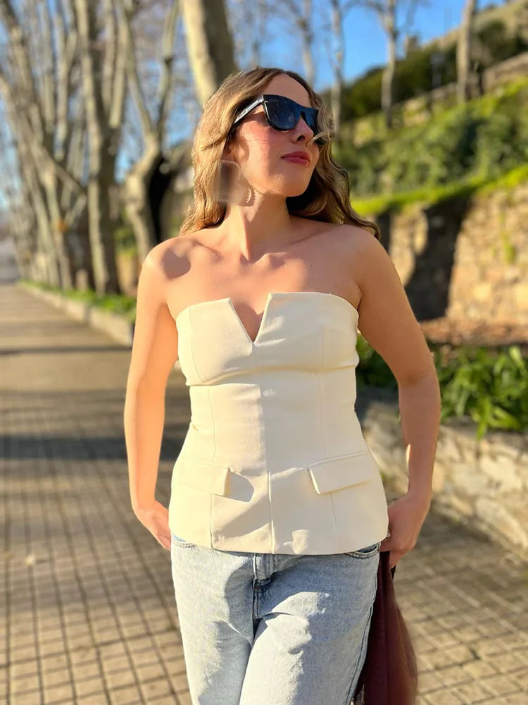Woman wearing a strapless top and sunglasses outdoors on a sunny day.