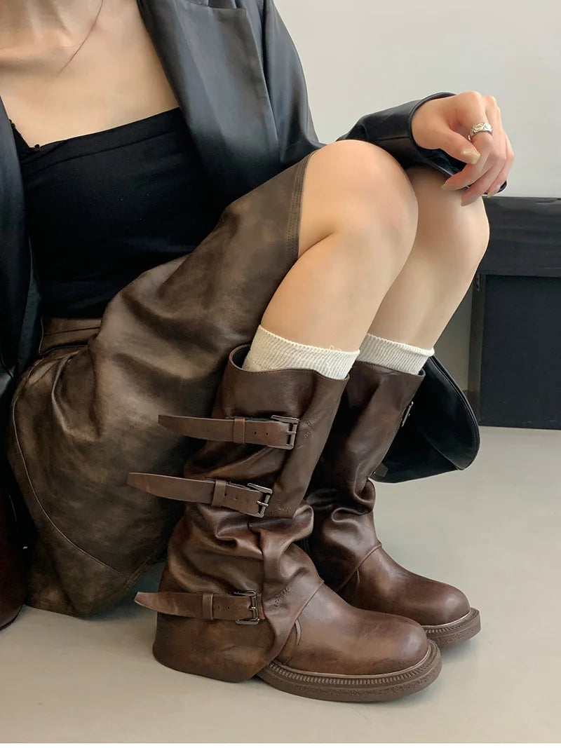 Person wearing brown knee-high boots with a neutral background