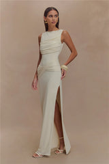 Woman wearing a long, light-colored dress with a slit on a beige background