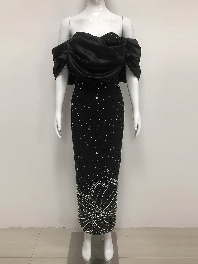Black evening gown with floral embellishments on a mannequin against a white background