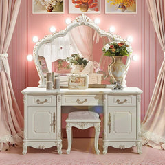 White vanity table with mirror, stool, and decorative items against a pink wall.