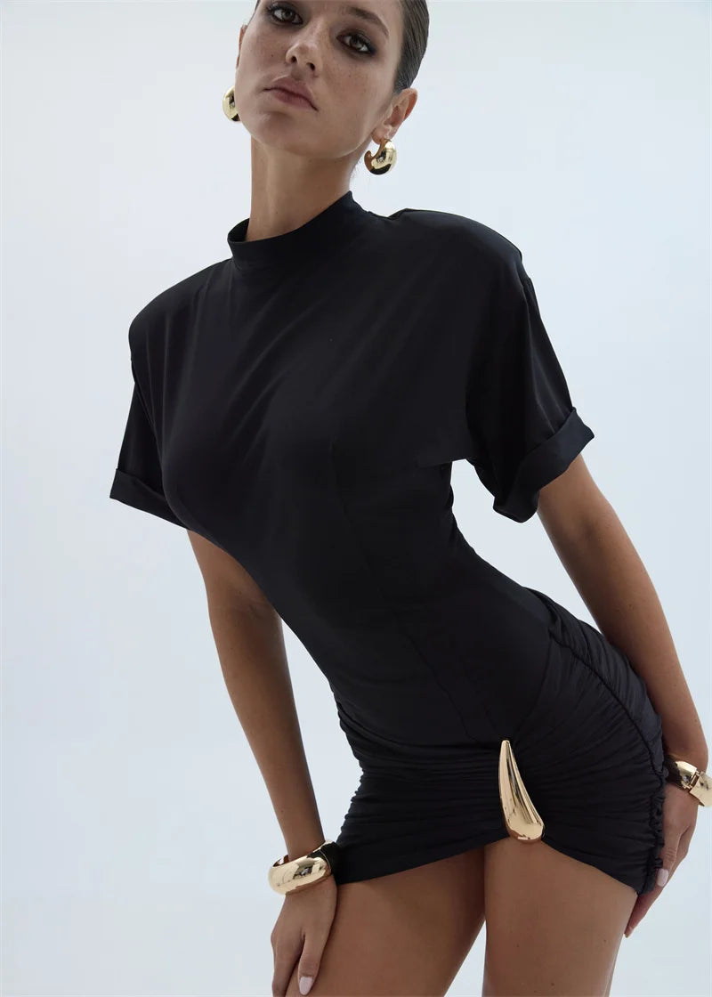 Woman wearing a black outfit with gold accents on a light gray background