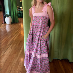 Woman wearing a pink floral dress with a green curtain background