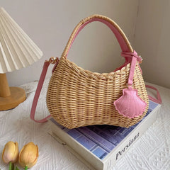 Wicker handbag with pink accents on a book next to tulips and a lamp.
