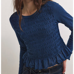 Blue textured long-sleeve top worn by a person on a white background