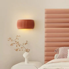 A French cream pumpkin wall lamp casting a soft glow in a cozy bedroom with a rustic wood headboard. B