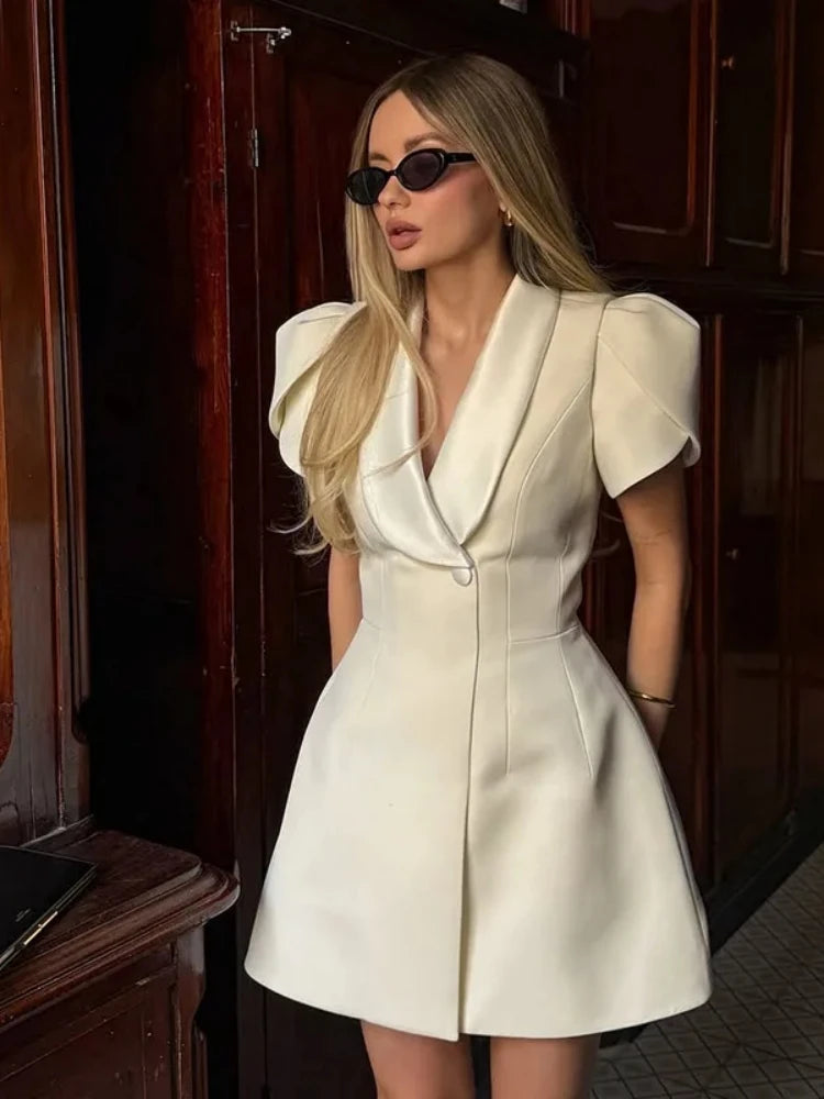 Woman wearing a white dress with puffed sleeves in an indoor setting.