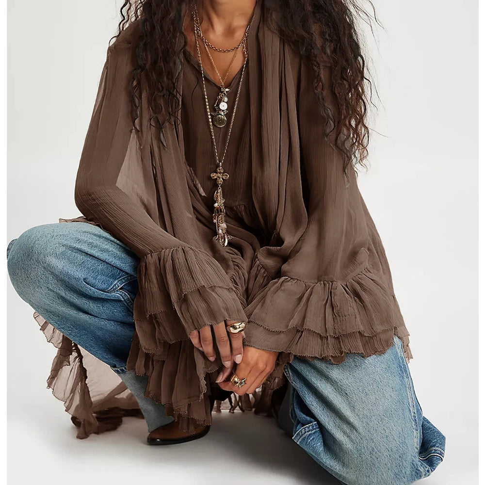 Person wearing a brown ruffled blouse and blue jeans on a white background