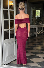 Woman in a burgundy off-shoulder lace dress standing in a room with a checkered floor.