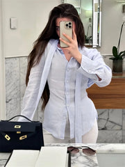 Person wearing a white shirt in a bathroom setting with a black handbag and sunglasses on a surface.