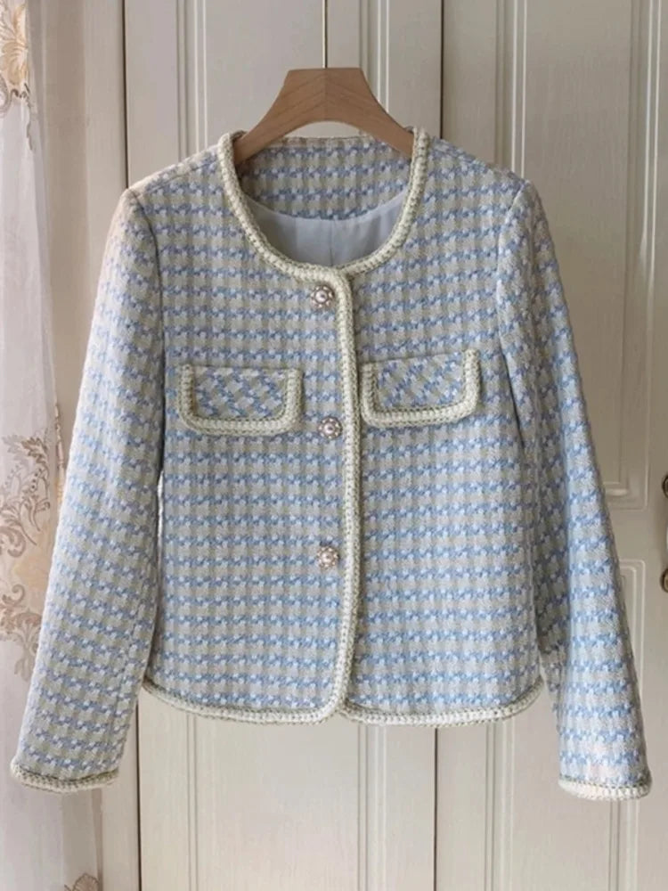 Light blue textured jacket with white trim on a wooden hanger against a neutral background