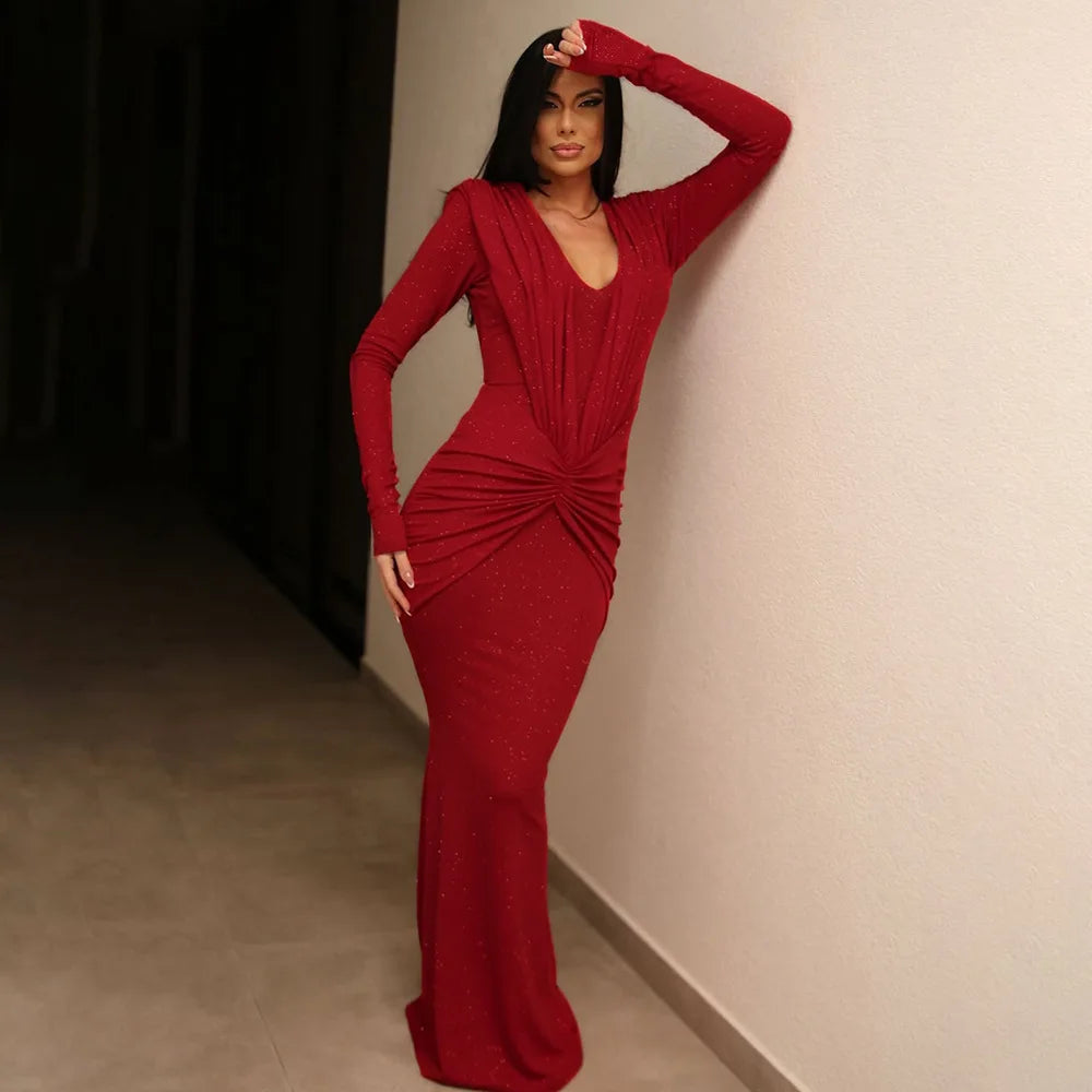 Woman in a red dress posing against a neutral wall.