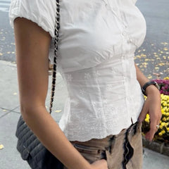 Person wearing a white blouse with floral patterns outdoors