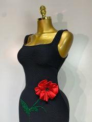 Close-up of the bodice on a black body-skimming gown showcasing a red floral appliqué.
