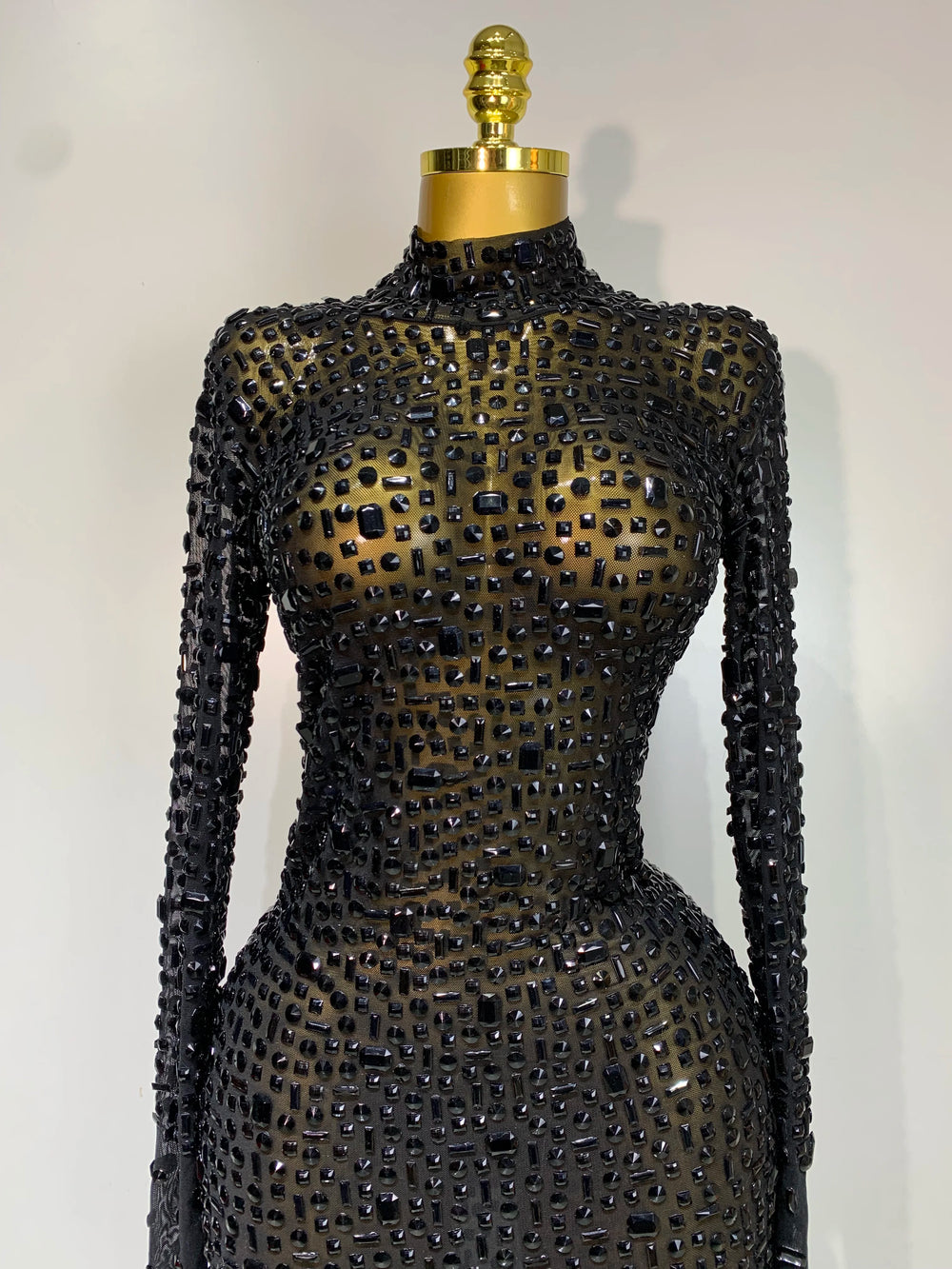 Black beaded dress on a mannequin against a white background