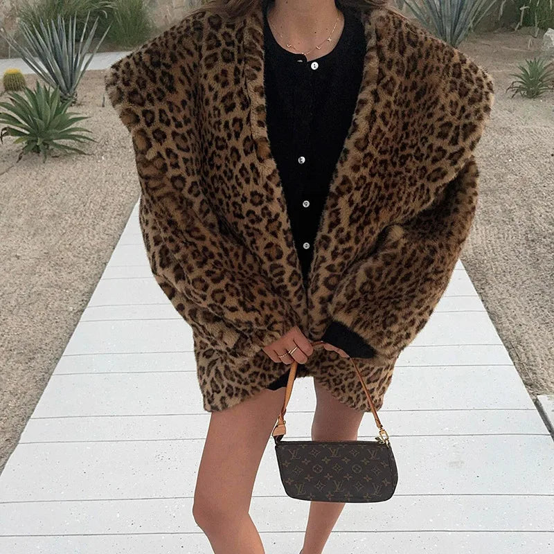 Person wearing a leopard print coat with a black handbag on a wooden path.