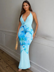 Model in a blue floral print halter neck maxi dress leaning against a wall