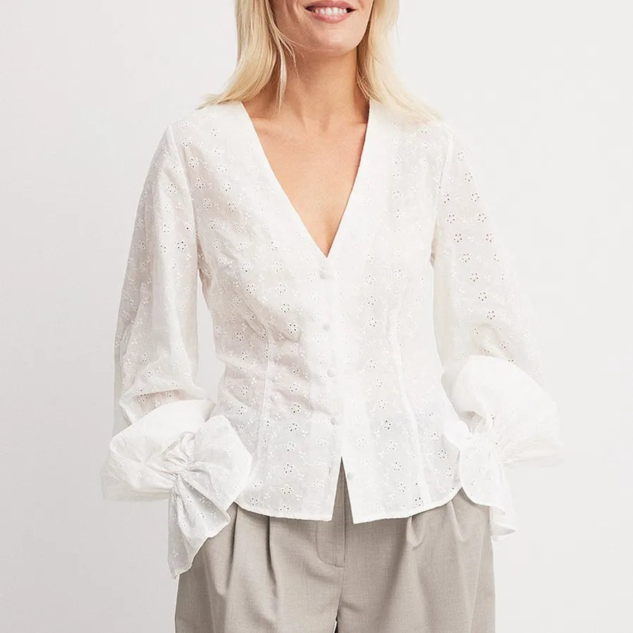 Woman wearing a white blouse with a plain background