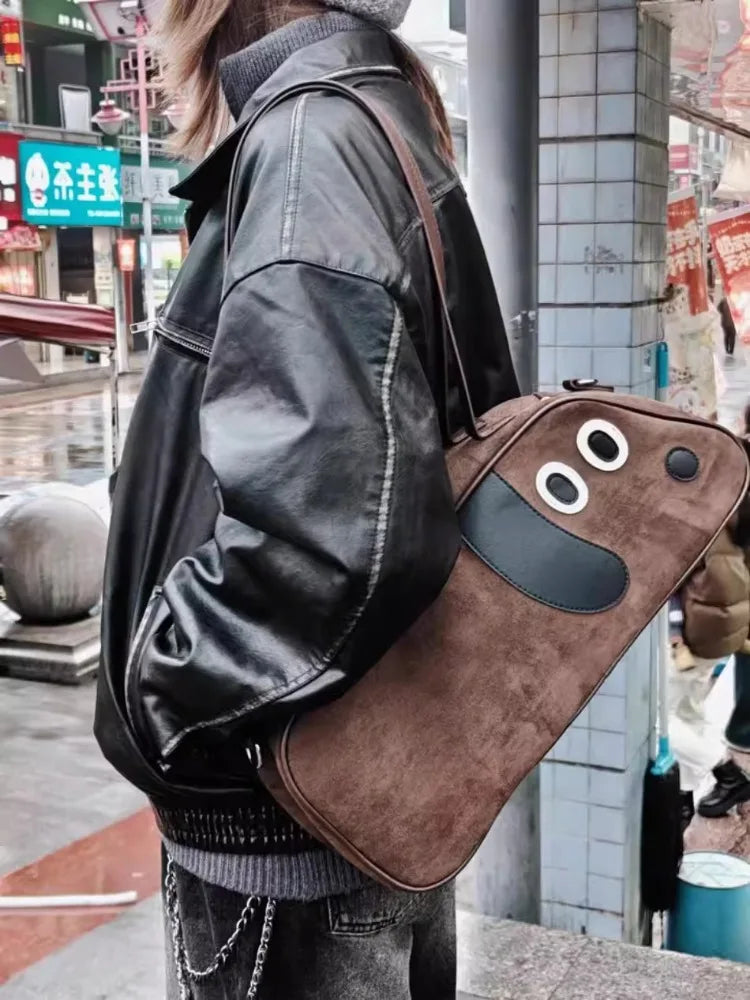 Person carrying a brown bag with cartoonish face design on a city street.