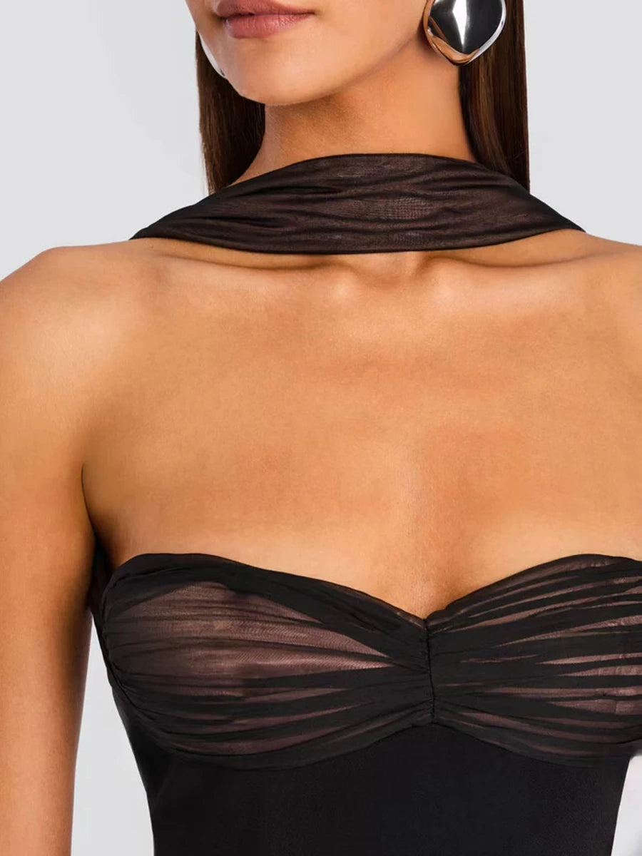 Black sheer top worn by a model on a plain background