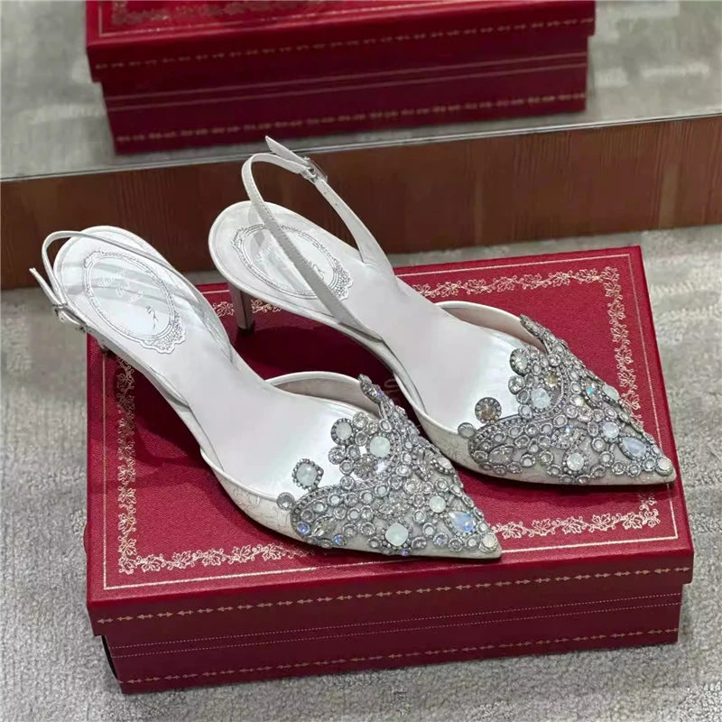 White high-heeled shoes with silver embellishments on a red box