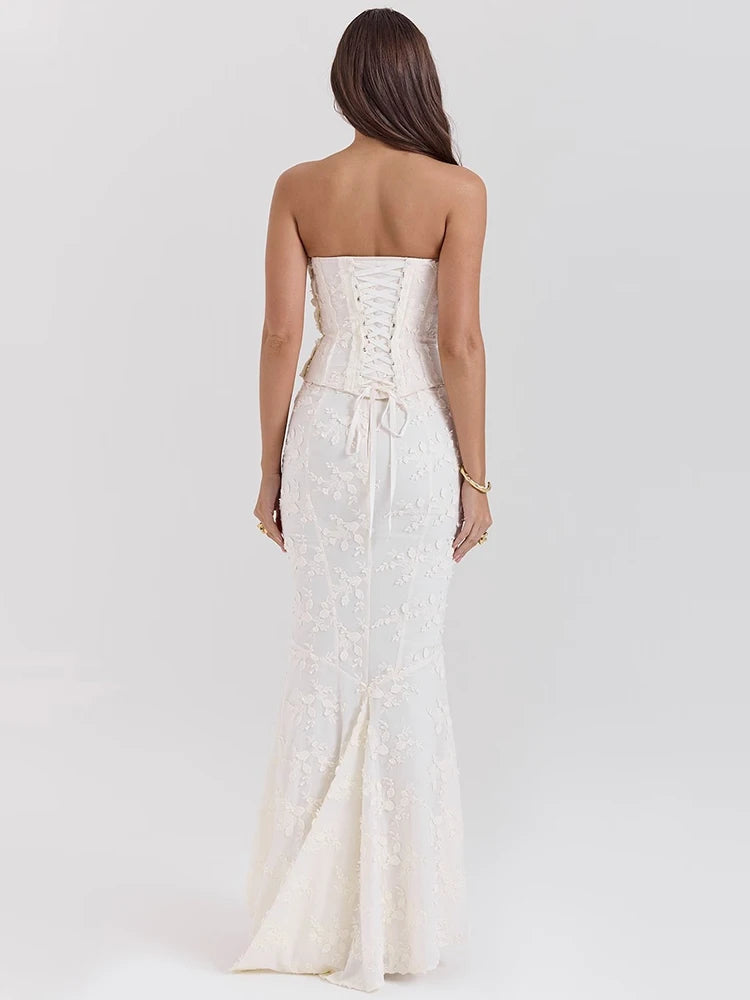 Woman wearing a strapless white lace dress on a plain background