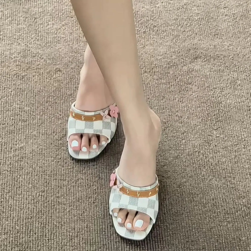 Pair of open toe heeled slippers with checkered pattern and floral accents