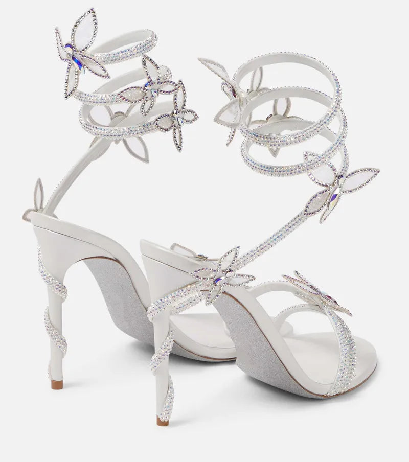 White high-heeled sandals with butterfly embellishments