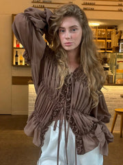 Woman wearing a brown fringed top in a store setting