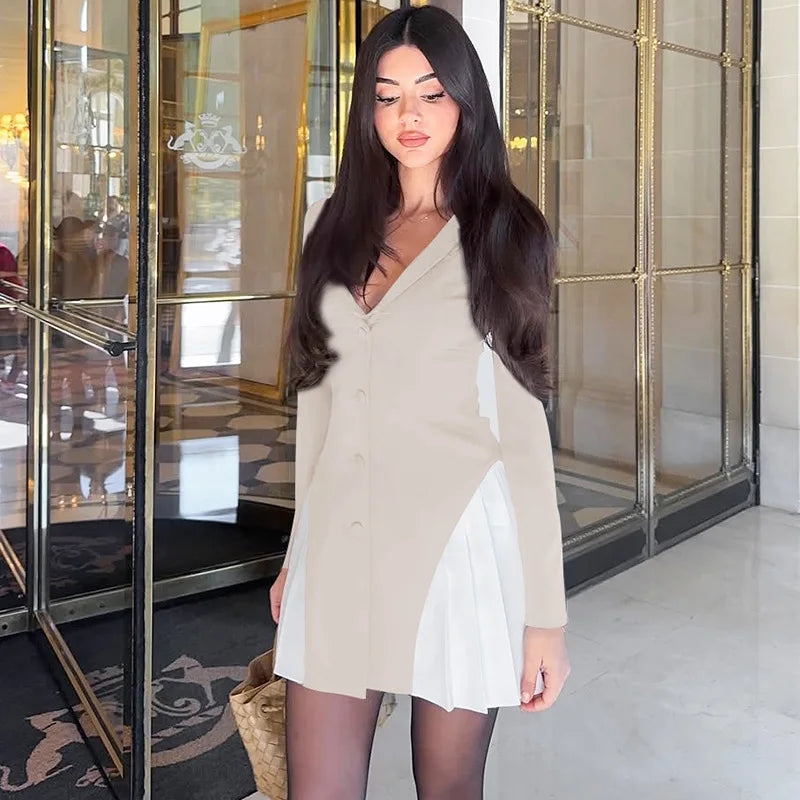 Woman in a beige dress standing in front of a glass door.