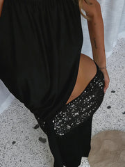 Person wearing a black dress with a sequin panel on a speckled floor.