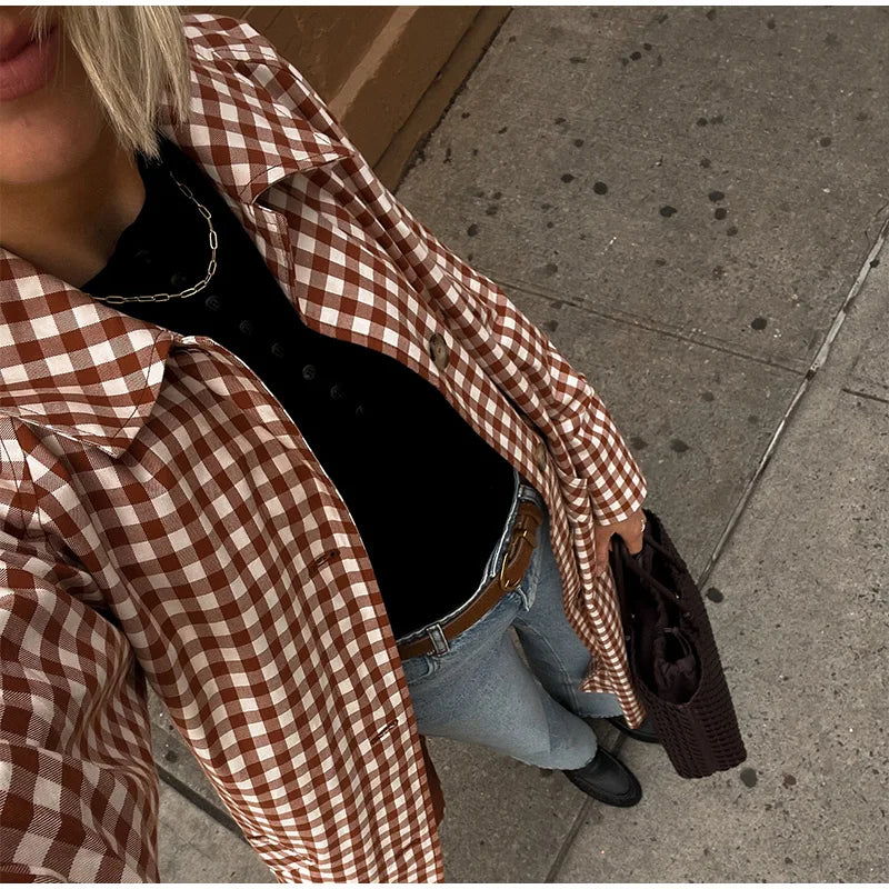 Person wearing a brown and white checkered shirt on a sidewalk.
