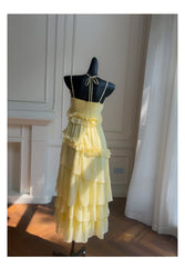 Yellow ruffled chiffon maxi dress on a black mannequin, back view showing tie closure.