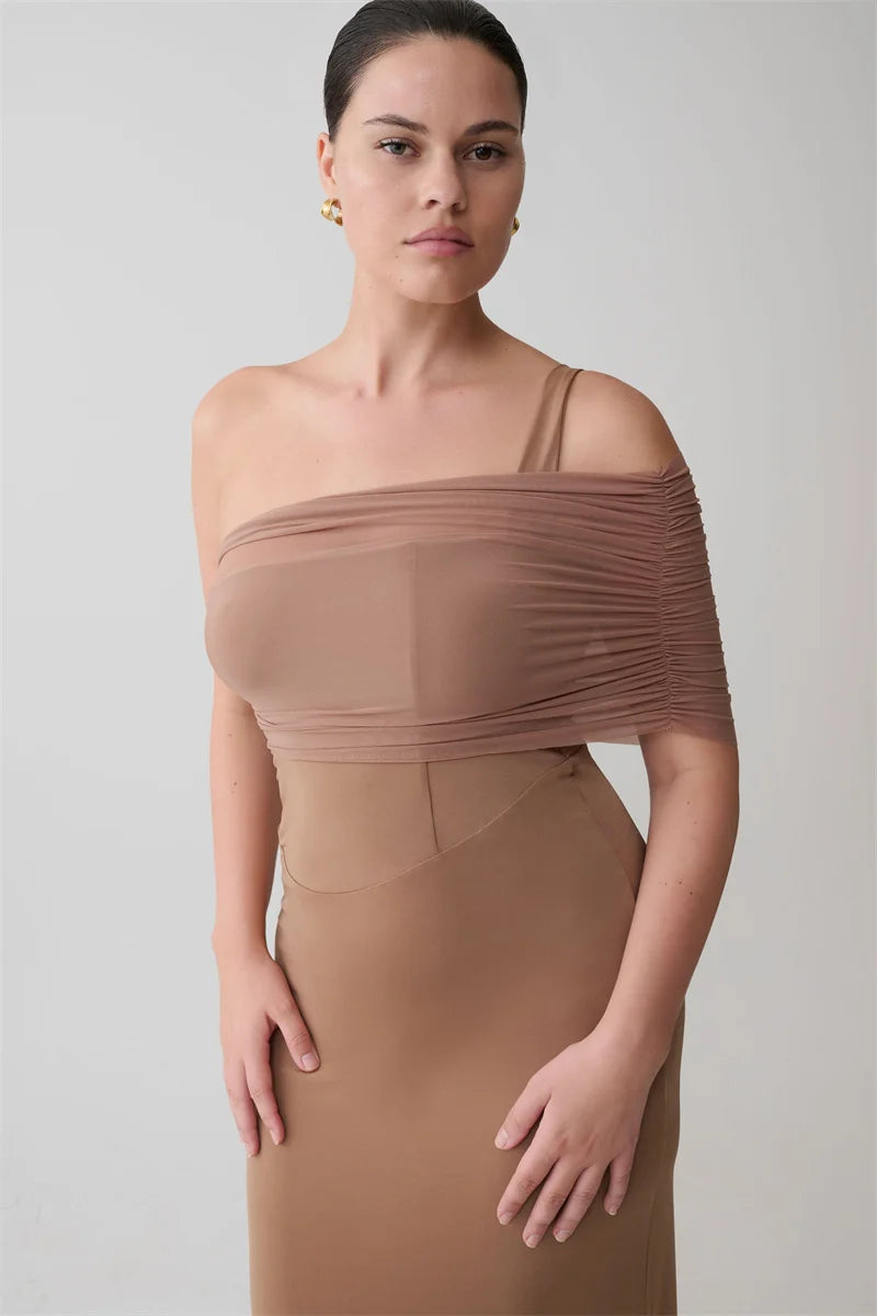Woman wearing a brown off-shoulder dress against a plain background