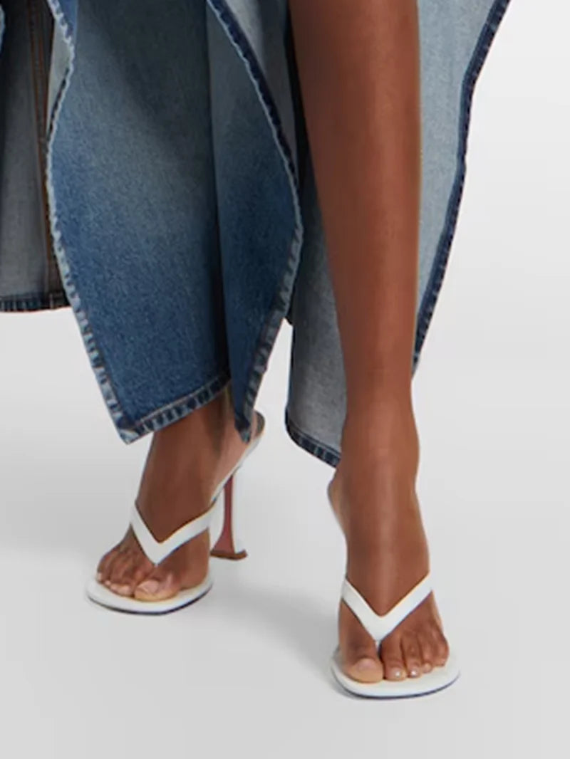 Close-up of a foot wearing a white flip flop heel with a flared heel.