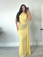 Woman taking a mirror selfie wearing a yellow one-shoulder dress with a sequined waist.