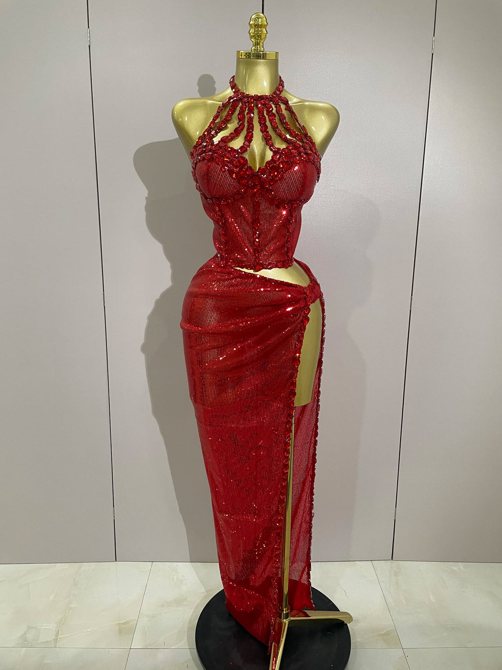 Red beaded evening gown on a mannequin against a plain background