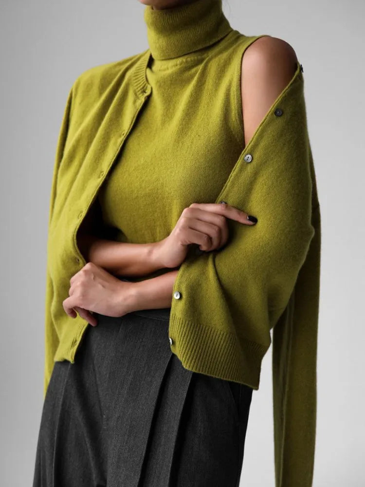 Green cardigan with cut-out shoulders worn by a person on a gray background