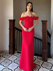 Woman in a red off-shoulder dress standing in a room with decorative tiles and wooden railings.