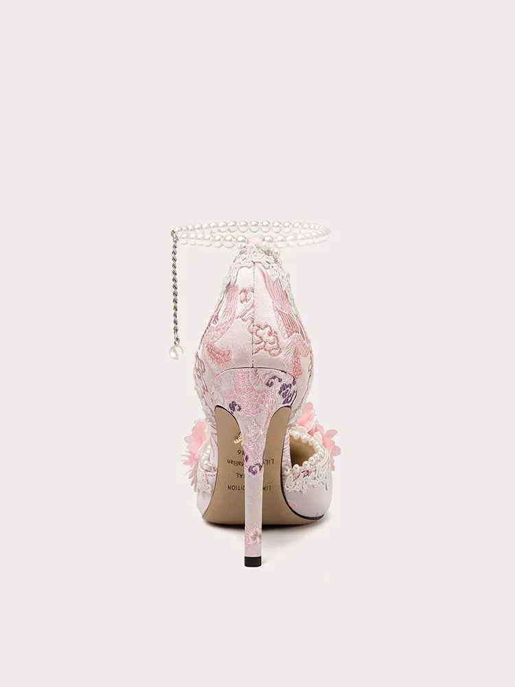 Floral high-heeled shoe with decorative chain on a light pink background