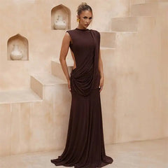 Model wearing a brown draped mock neck sleeveless maxi dress in an outdoor setting
