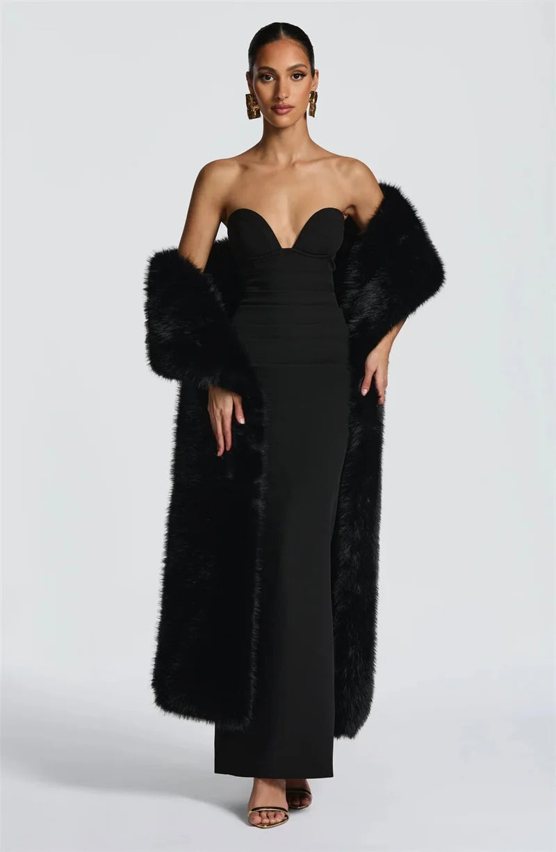 Woman wearing a black strapless gown with a fur stole on a white background
