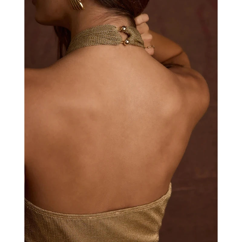 Close-up of a person wearing a gold choker necklace with a blurred background