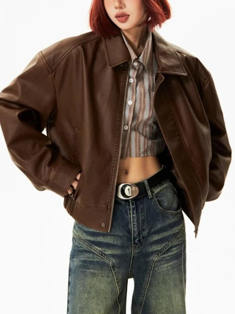 A woman wearing a brown cropped faux leather biker jacket with zipper details. Golden Atelier 1 