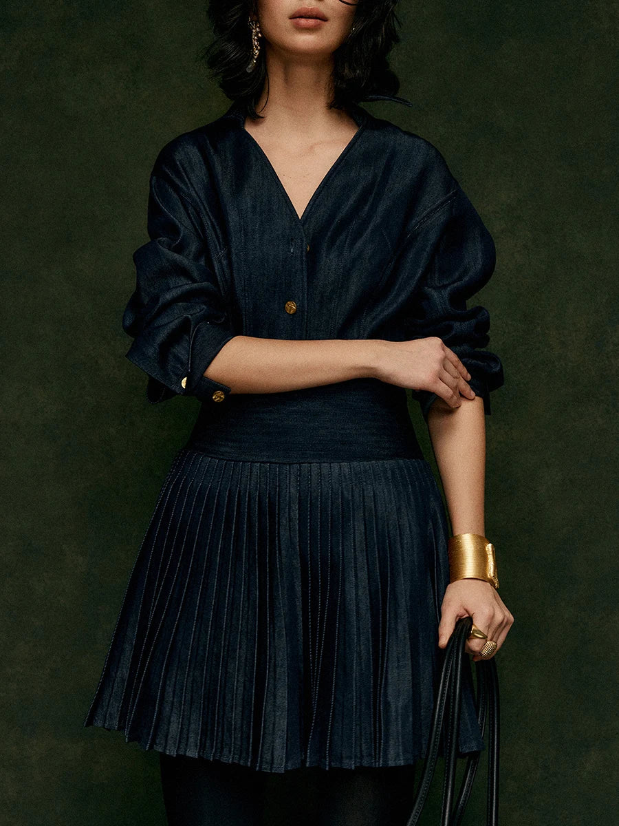 Woman wearing a dark blue pleated dress against a dark green background