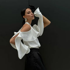 Woman wearing a white blouse with ruffled sleeves against a black background