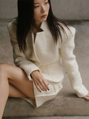 Woman in a beige outfit sitting on a textured surface
