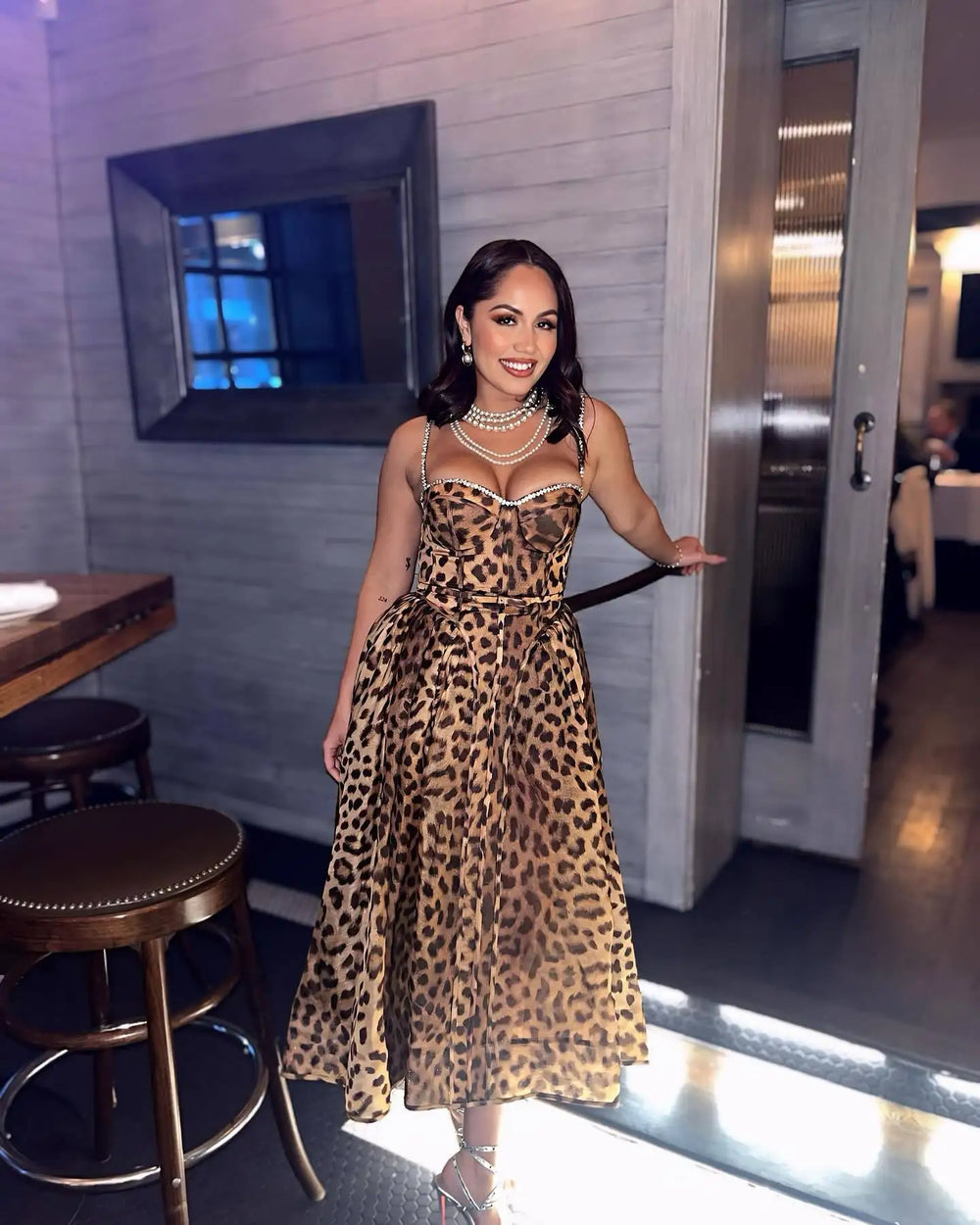 Woman in a leopard print dress standing in a restaurant setting