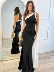 Woman wearing a black and white dress standing in front of a mirror.